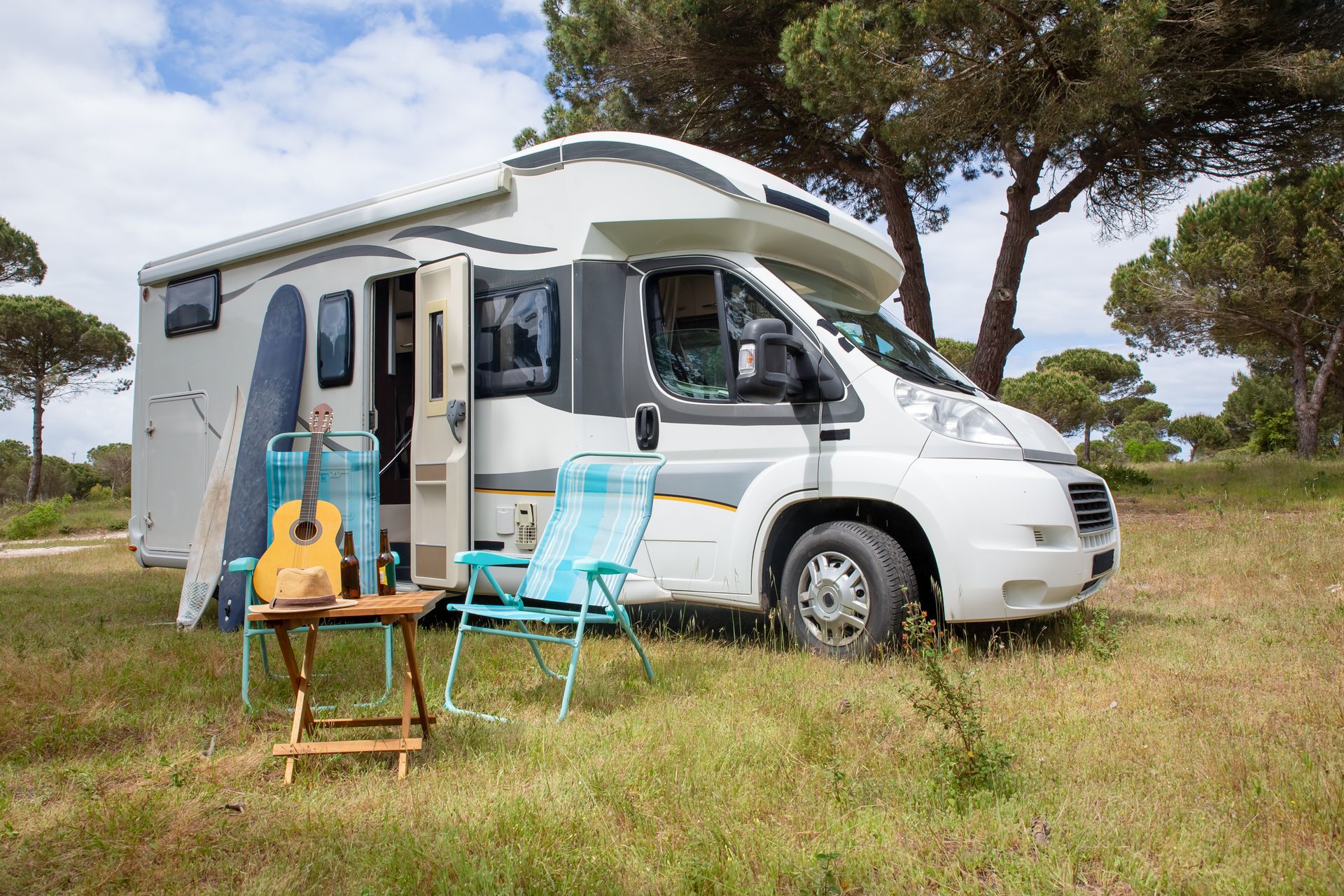 RV lifestyle scene with surfboards and guitar at a campsite